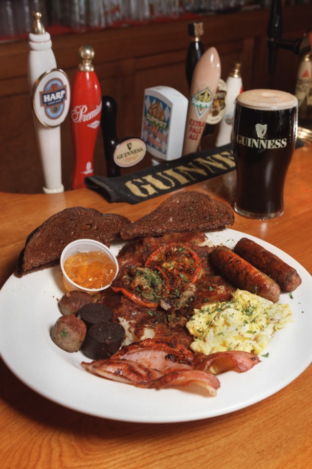 a guinness glass sits on a table next to a plate of food