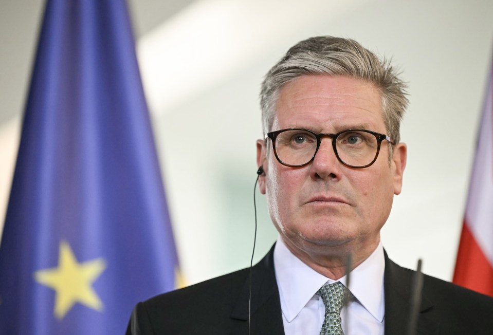 a man wearing glasses stands in front of a flag with a yellow star