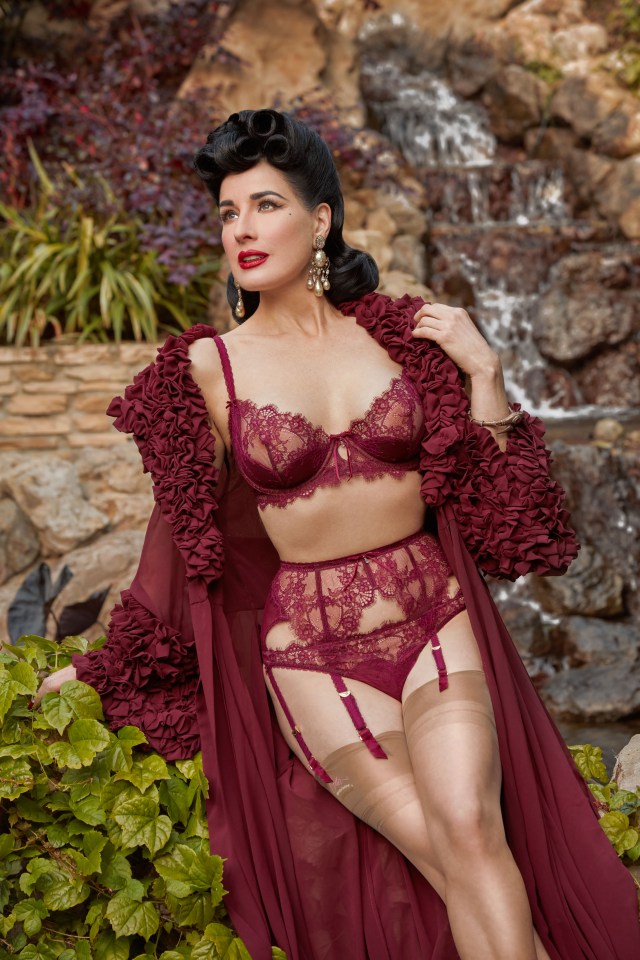a woman in lingerie stands in front of a waterfall