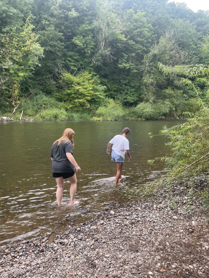 two people standing in a river with trees in the background