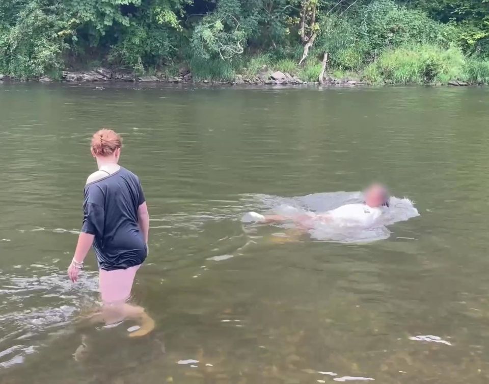 a woman in a black shirt stands in a river next to a man in a white shirt
