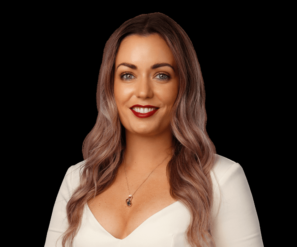 a woman wearing a white top and a necklace smiles for the camera