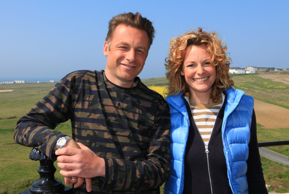 a man in a camo shirt stands next to a woman in a blue vest