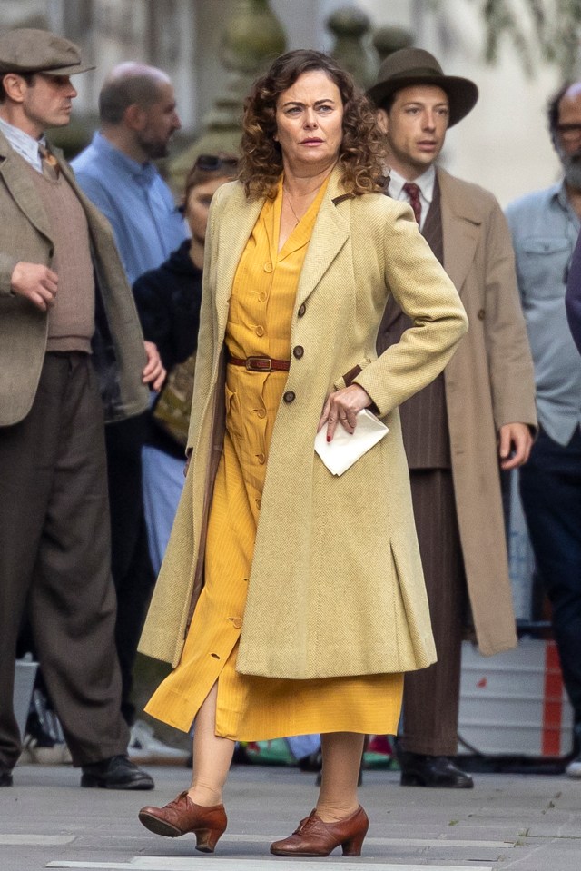 a woman in a yellow coat holds a piece of paper