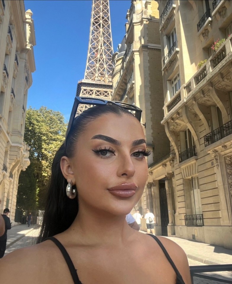 a woman wearing sunglasses stands in front of the eiffel tower