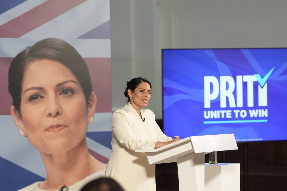 a woman stands at a podium in front of a prity unite to win sign
