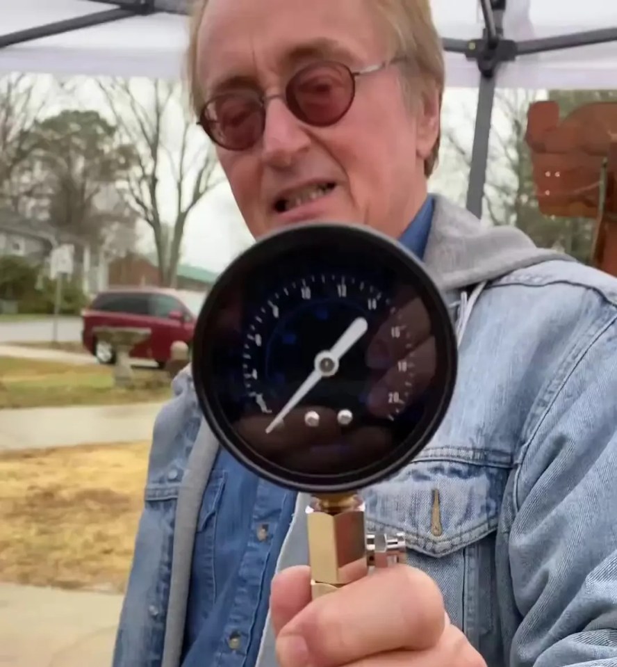 a man in a denim jacket is holding a pressure gauge with the number 10 on it