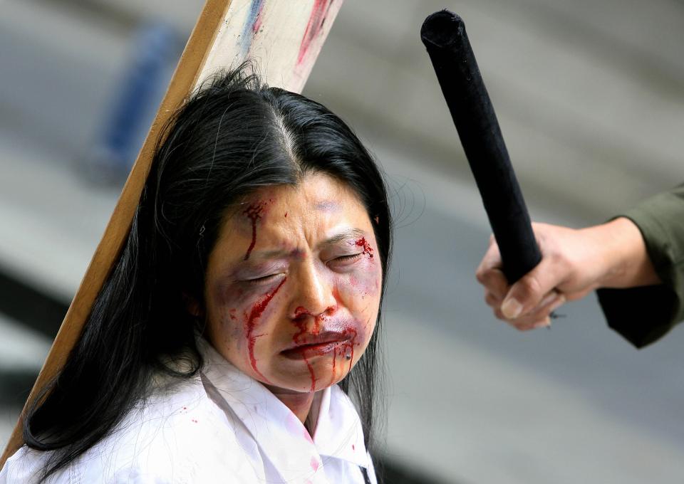Sydney, AUSTRALIA: Falungong practitioners act out a torture scene as they protest in Sydney, 03 April 2006. Members of the Falungong religious movement were bringing to the public's attention what they claim is the Chinese government's torture and abuse of their fellow practitioners. The demonstration came as Australia and China signed a landmark nuclear safeguards pact in Canberra, 03 April, in the presence of Chinese Premier Wen Jiabao and his Australian counterpart John Howard. AFP PHOTO/Greg WOOD (Photo credit should read GREG WOOD/AFP/Getty Images)