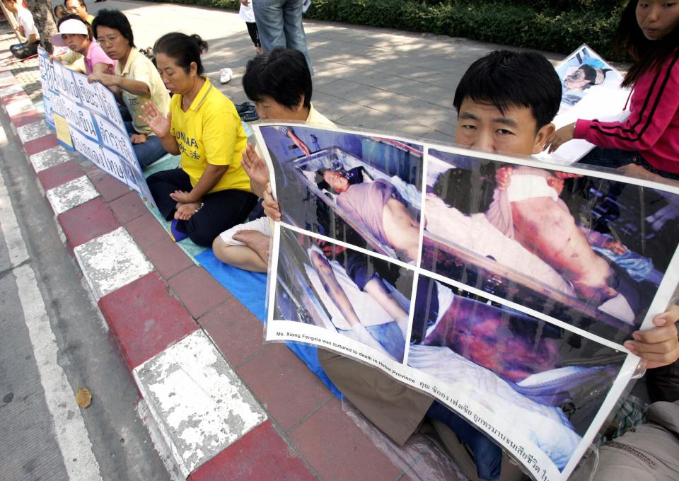 BANGKOK, THAILAND: Members of the Falun Gong religious group hold protest banners while meditating during a protest opposite to the Chinese embassy in Bangkok, 13 December 2005. The religious movement -- also known as Falun Dafa -- is a Chinese spiritual discipline for the mind and body, according to its British website, and its members frequently protest around the world against the use of violence by Chinese police against fellow members in China. AFP PHTO/PORNCHAI KITTIWONGSAKUL (Photo credit should read PORNCHAI KITTIWONGSAKUL/AFP/Getty Images)