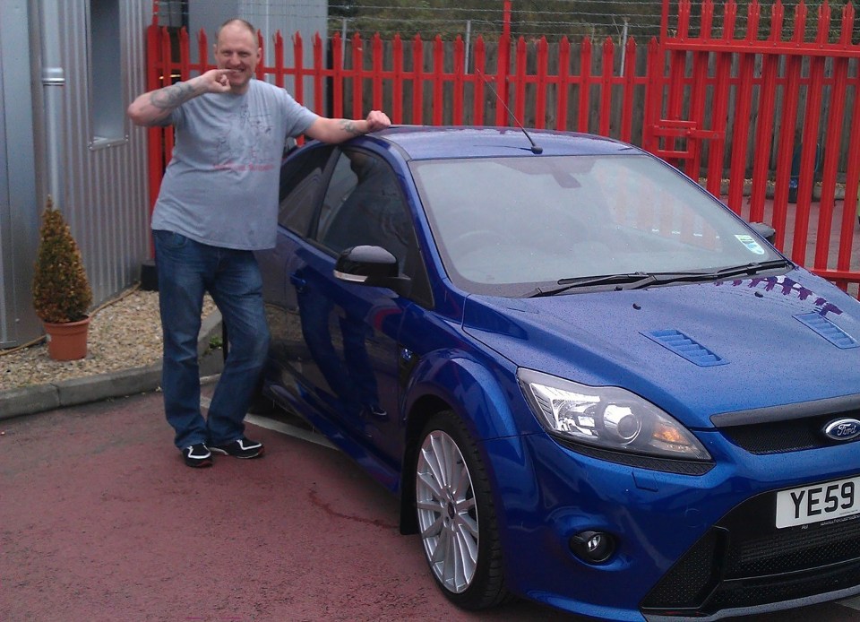 a man is standing next to a blue ford car