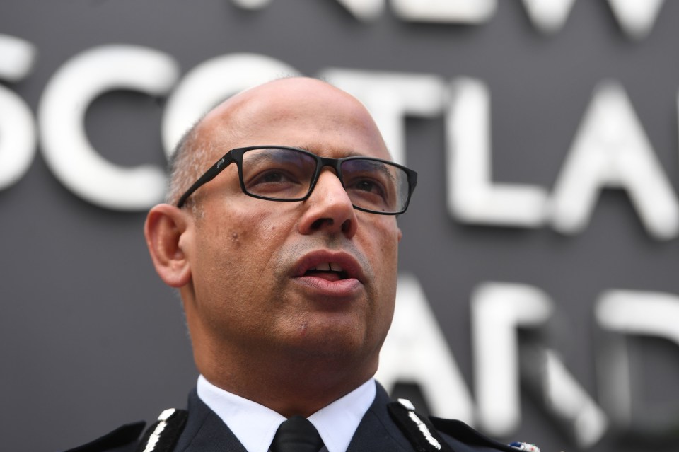 a man wearing glasses stands in front of a sign that says scotland