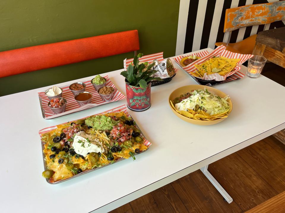 a tray of nachos sits on a table next to a bowl of guacamole