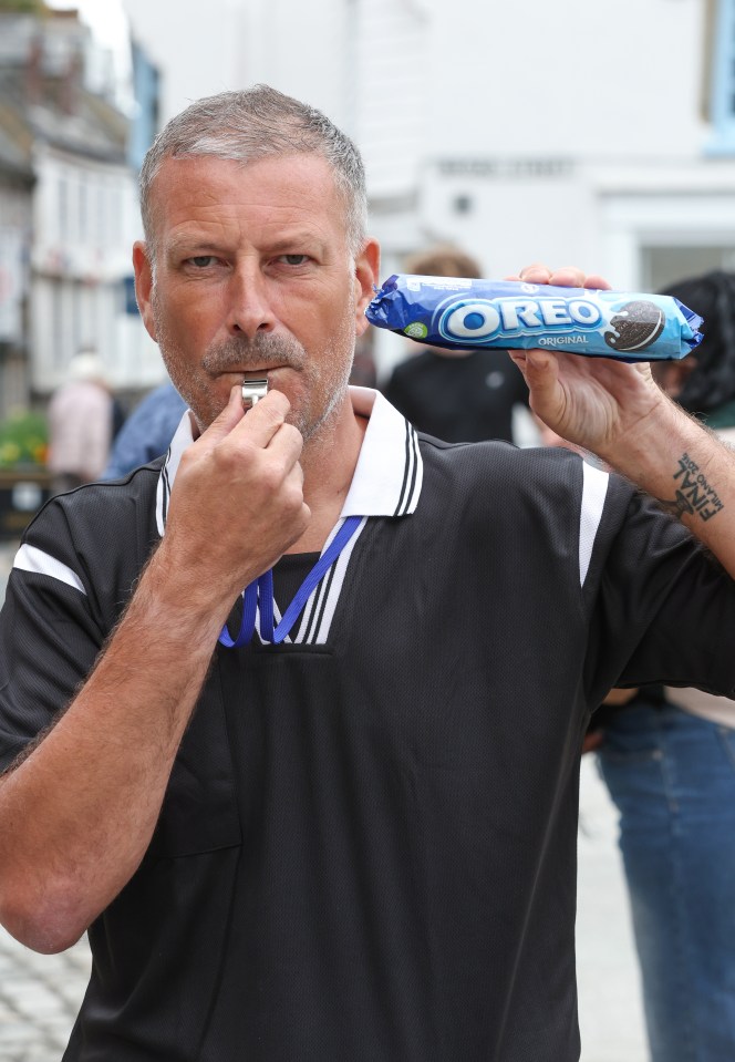 a man blowing a whistle while holding a package of oreo cookies