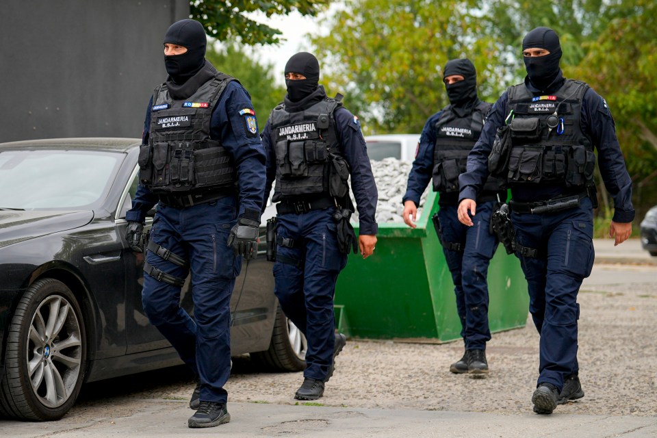 a group of police officers are walking in front of a black car