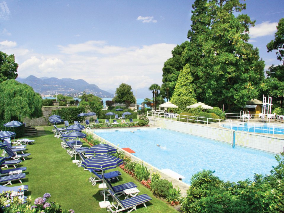 a swimming pool surrounded by chairs and umbrellas with mountains in the background