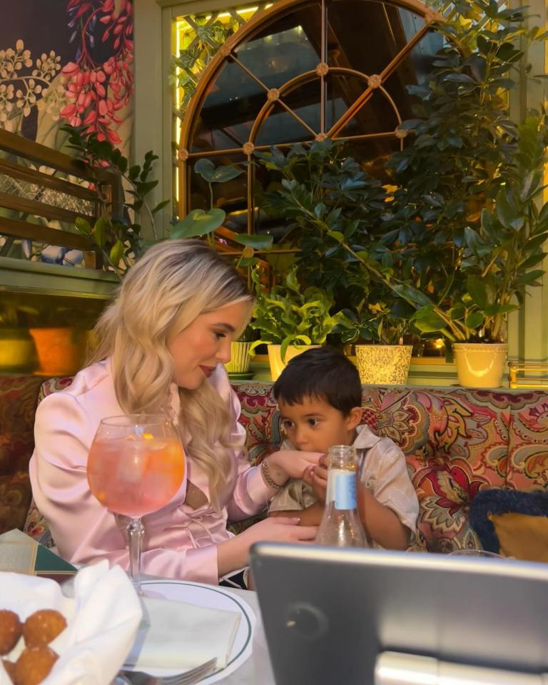 a woman sits at a table with a child and a bottle of san pellegrino