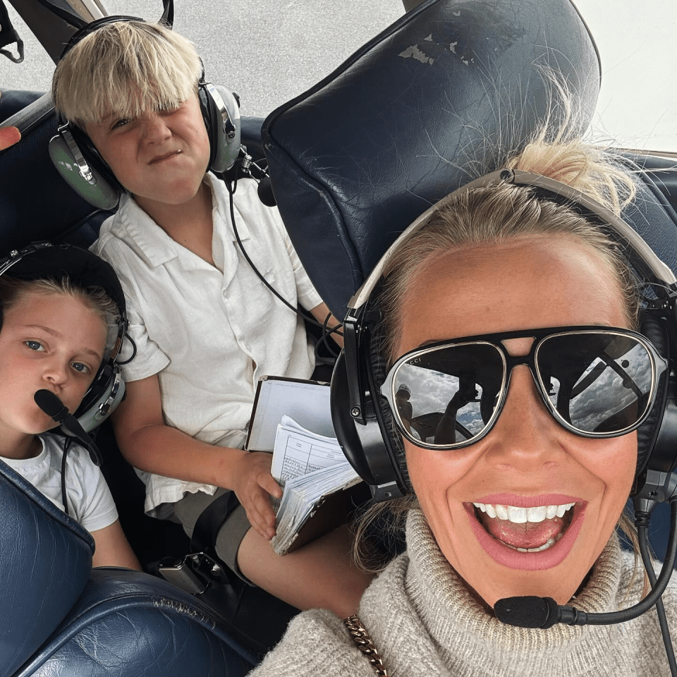 a woman wearing headphones and sunglasses is sitting next to two children