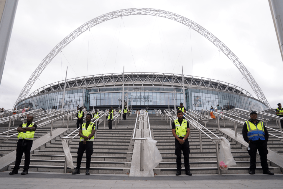 a group of men in yellow vests stand on the stairs of a stadium