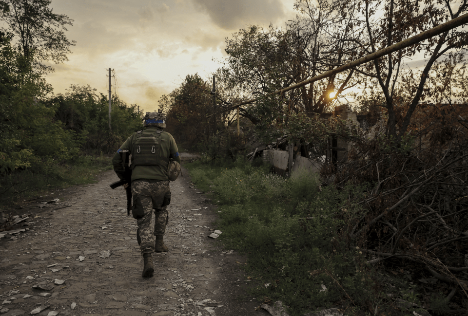 a soldier walking down a dirt road with the number 6 on his back