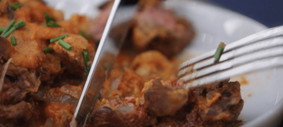 a fork is being used to cut a piece of meat on a plate