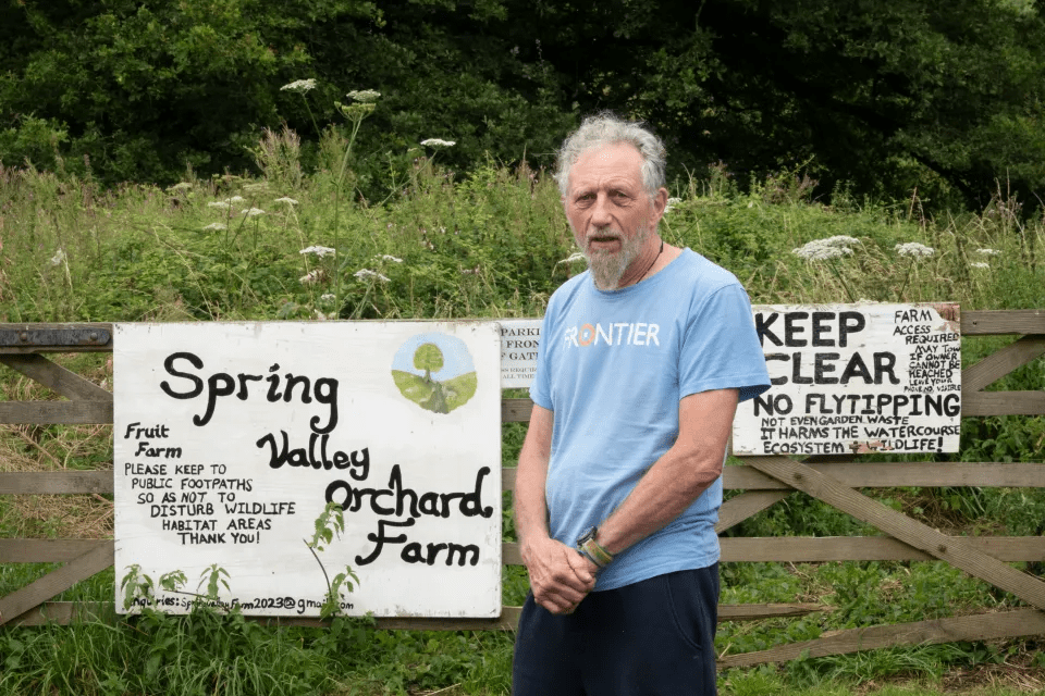 a man stands in front of a sign that says spring valley orchard farm