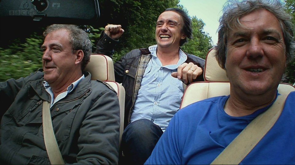three men are sitting in a car with a bbc logo on the rear view mirror