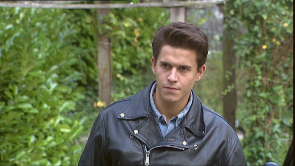 a man wearing a black leather jacket with gold buttons