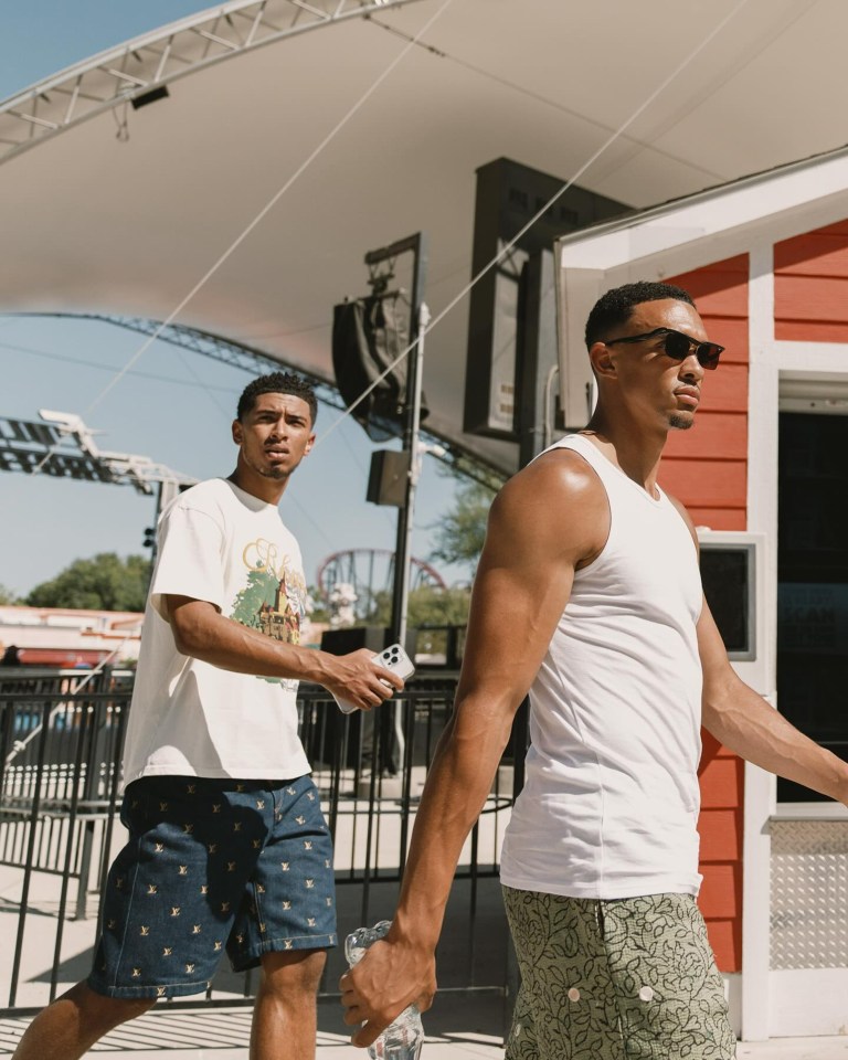 a man wearing a white tank top and shorts walks with another man