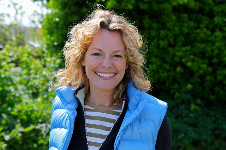 a woman wearing a blue vest smiles for the camera