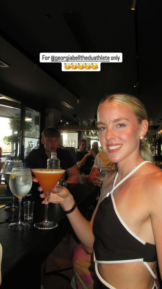 a woman holding a martini in front of a sign that says for @georgiabelltheduathlete only