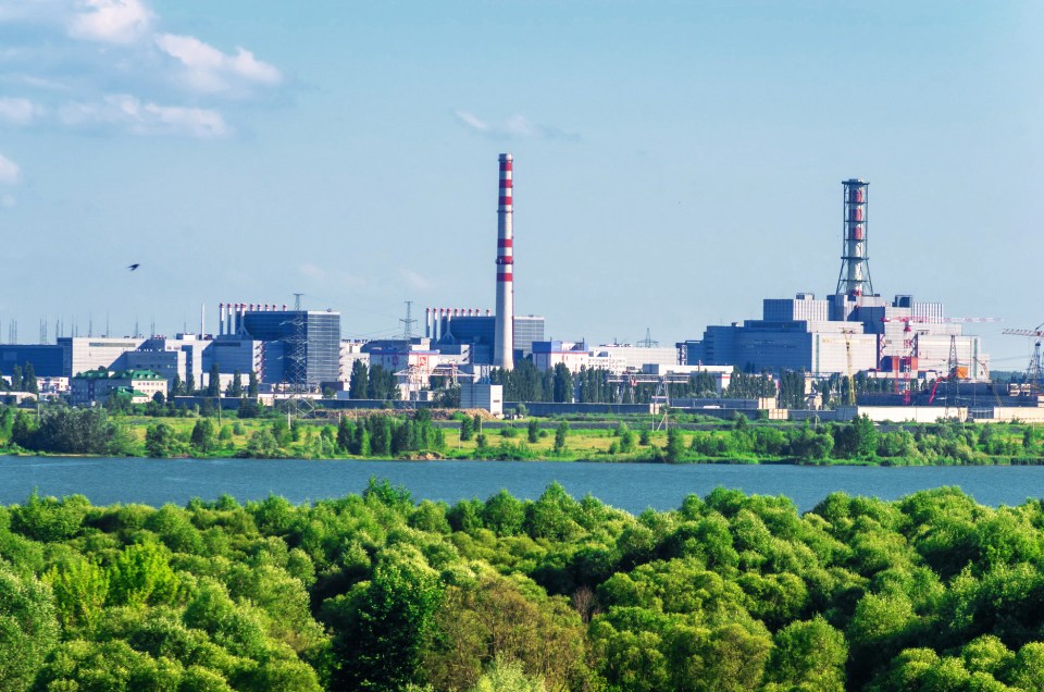 a large building with a red and white striped chimney is surrounded by trees and a body of water