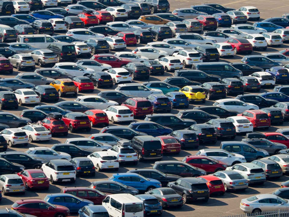 a lot of cars are parked in a parking lot one of which is a ford