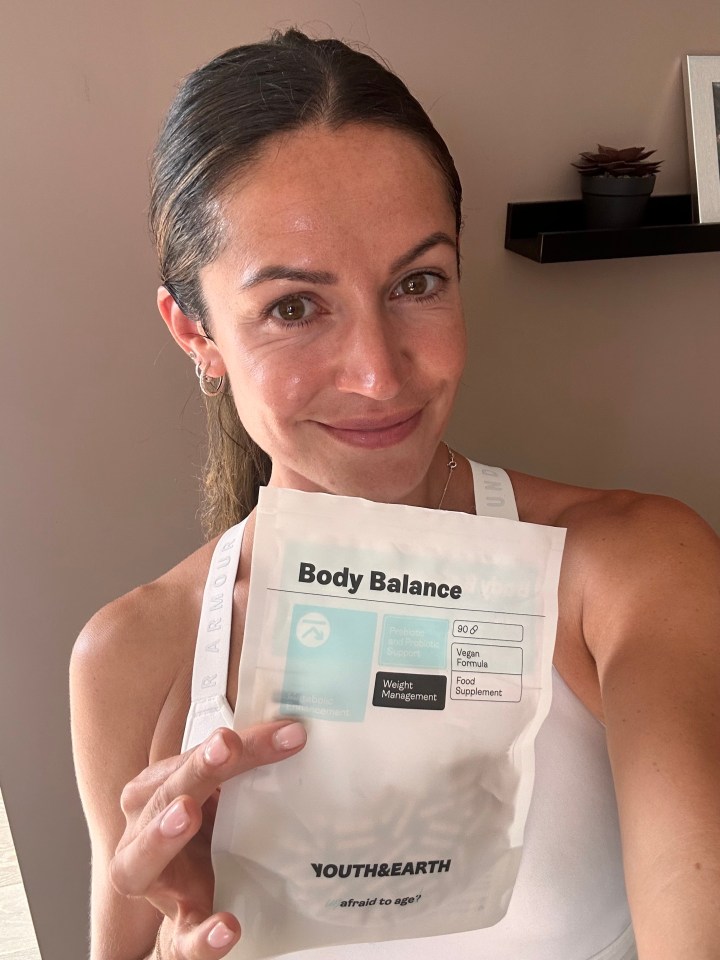 a woman is holding a package of body balance