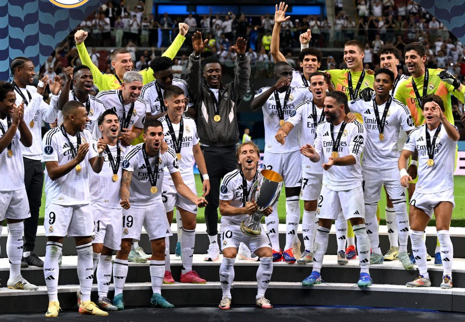 a group of soccer players are posing for a photo with a man holding a trophy that says fly emirates