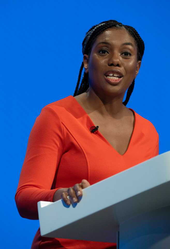 a woman in an orange dress stands at a podium with a blue background
