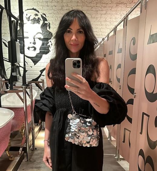 a woman in a black dress is taking a selfie in a bathroom .