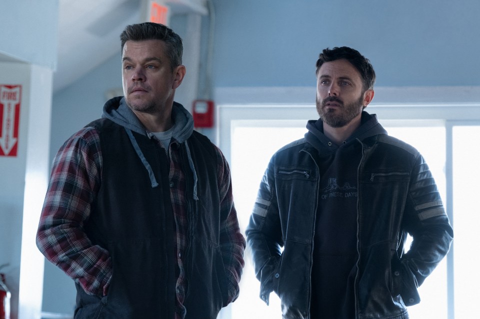 two men standing next to each other in front of a fire extinguisher