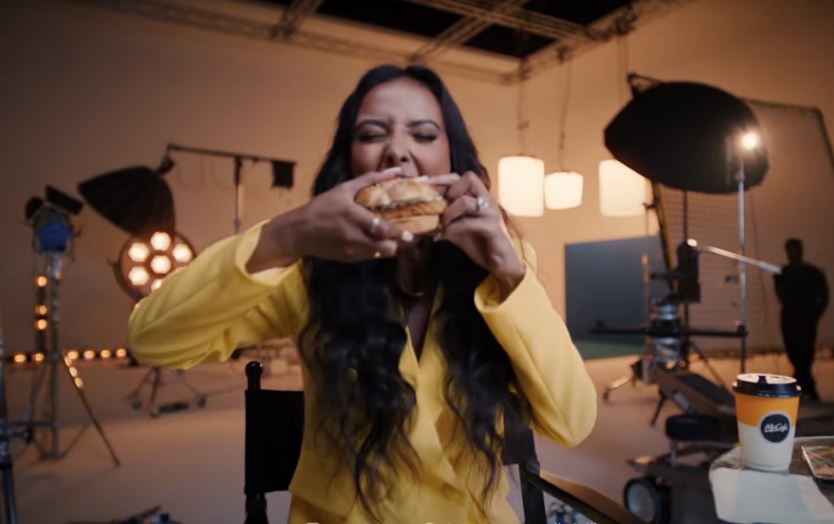 a woman in a yellow jacket is eating a hamburger