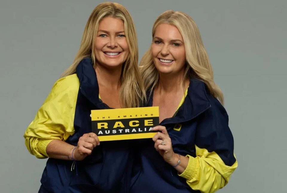 two women holding a sign that says the amazing race australia