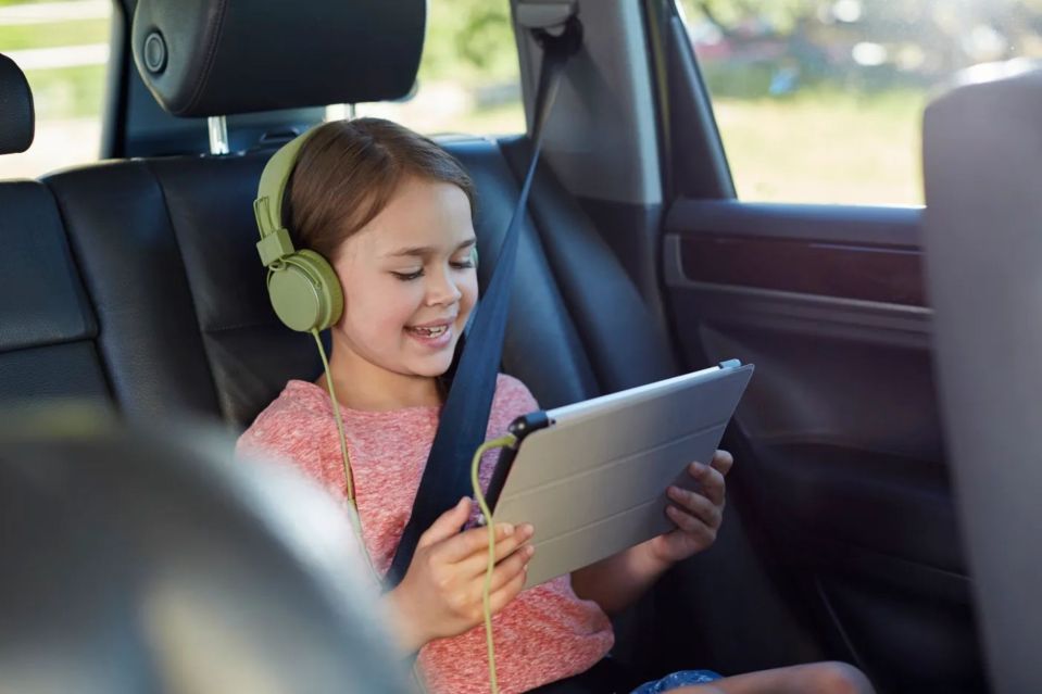 a little girl wearing headphones is using a tablet