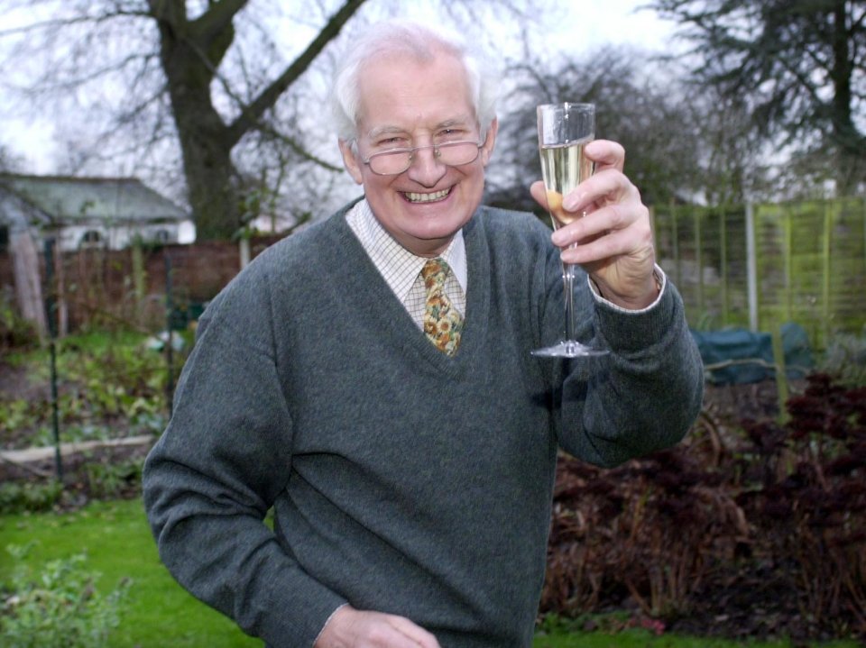 a man in a green sweater and tie is holding a glass of champagne