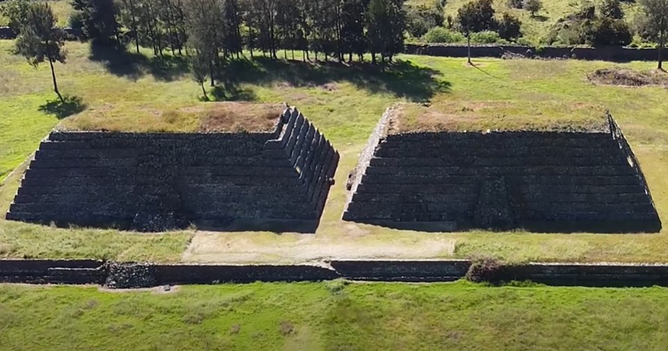an aerial view of two pyramids in a grassy field