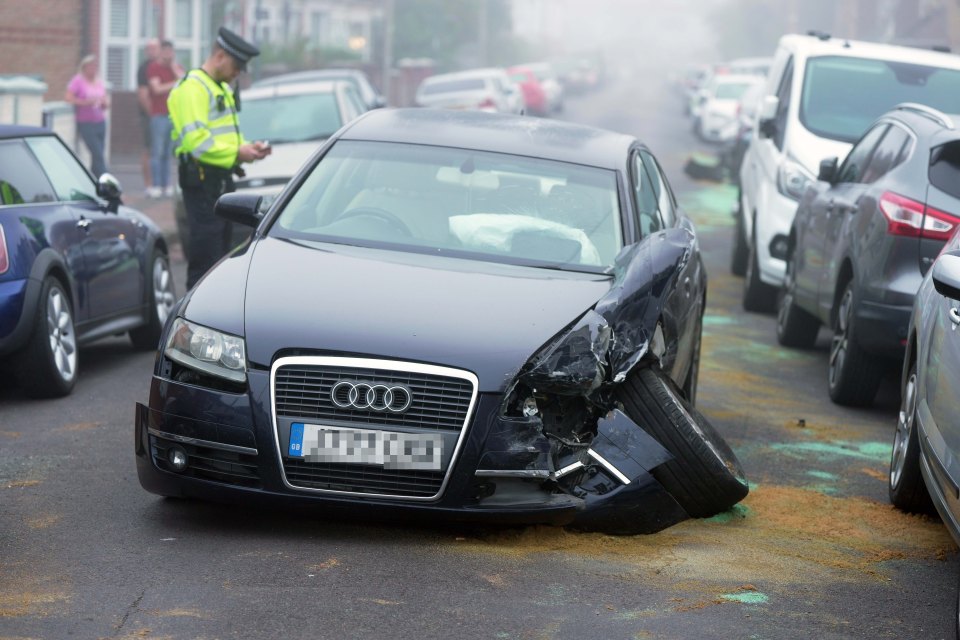 a police officer stands next to a damaged audi car