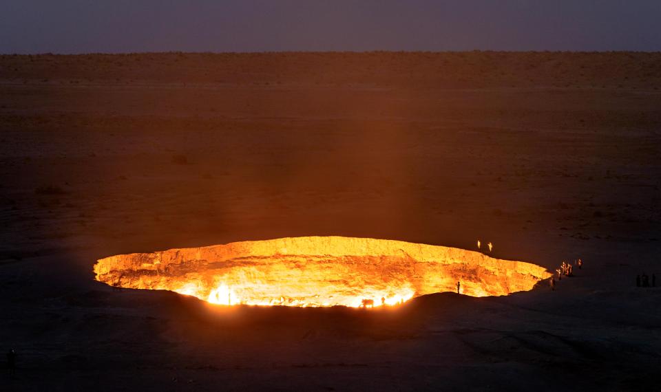 a sunset over a desert with two tents in the foreground