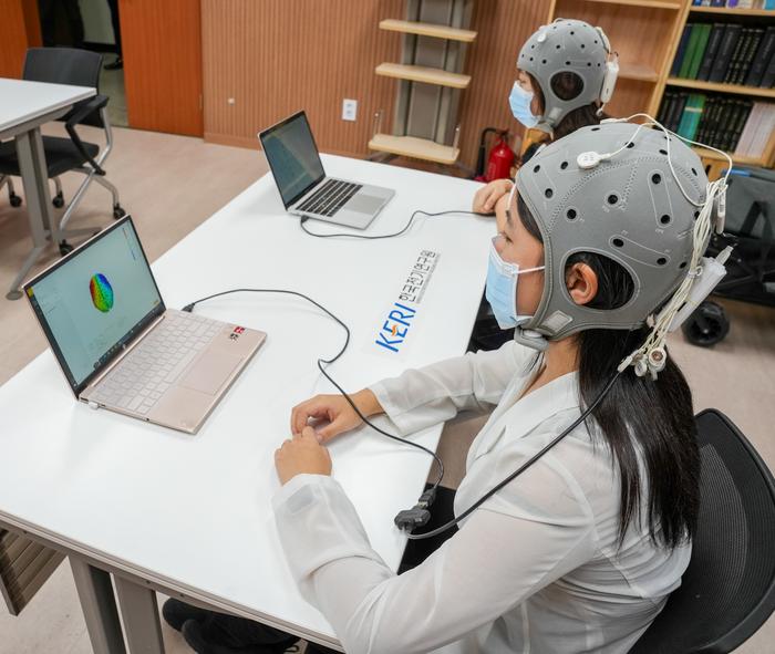 a woman wearing a helmet sits at a desk with a laptop and a sign that says keri