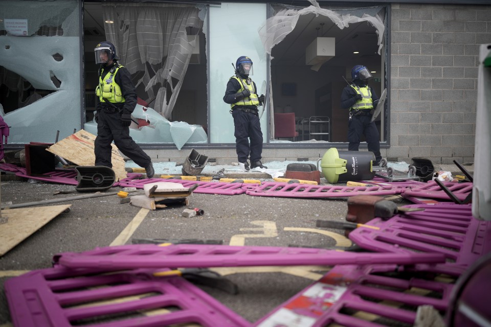 two police officers standing in front of a building with a broken window
