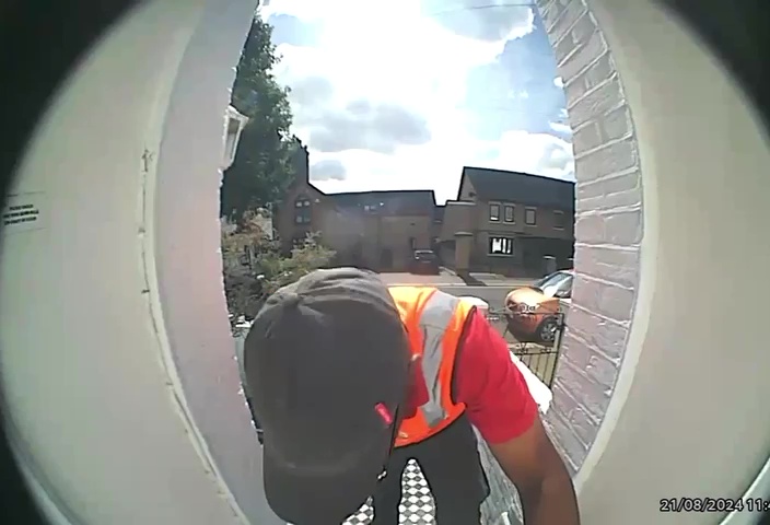 a man in an orange vest is looking through a door