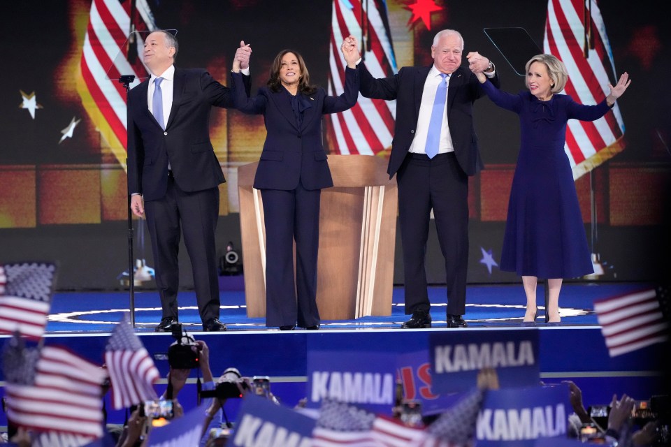 a group of people standing on a stage with signs that say kamala