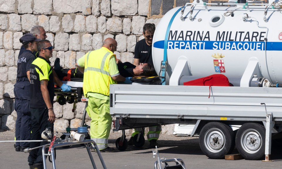 a man laying on a stretcher in front of a marina militare trailer