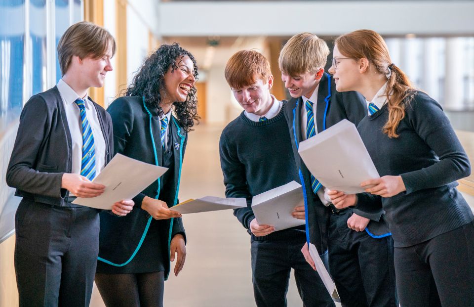 a group of students in school uniforms looking at papers